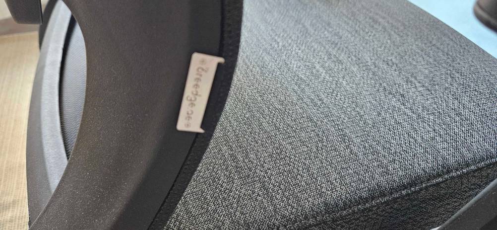 Detailansicht des Materials eines getesteten grauen Bürostuhls auf Rollen.