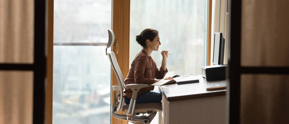Bürostuhl-Test: Eine Frau sitzt auf einem ergonomischen Bürostuhl mit hoher Rückenlehne und Nackenstütze in einem modernen Büro.