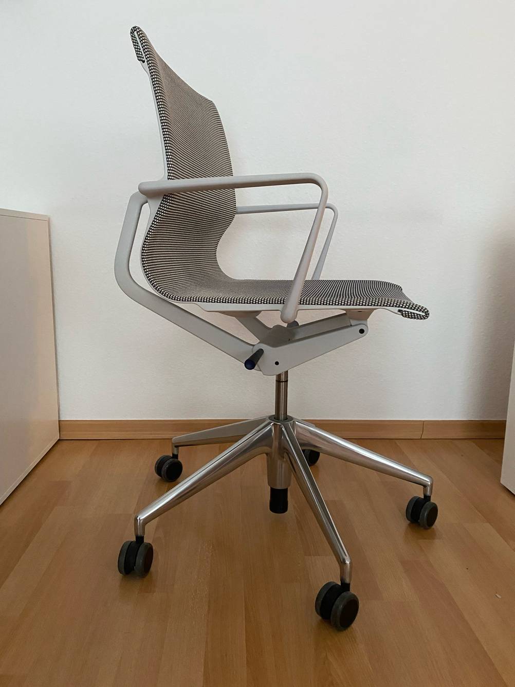 Ein getesteter Bürostuhl von der Seite vor einer hellen Wand auf einem Holzboden.