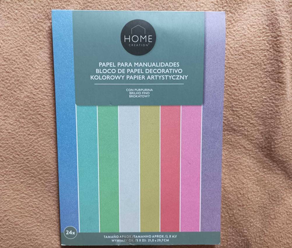 Das bunte Papier als Block auf einer beigen Decke.