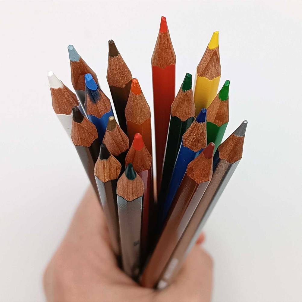 Die Spitzen mehrerer Buntstifte im Test von einer Hand gehalten.