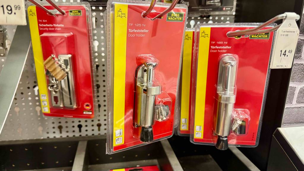 Mehrere Türfeststeller im Test hängen innerhalb ihren transparenten Kunststoffverpackungen inklusive roter Kartonbasis an einem Verkaufsregal.