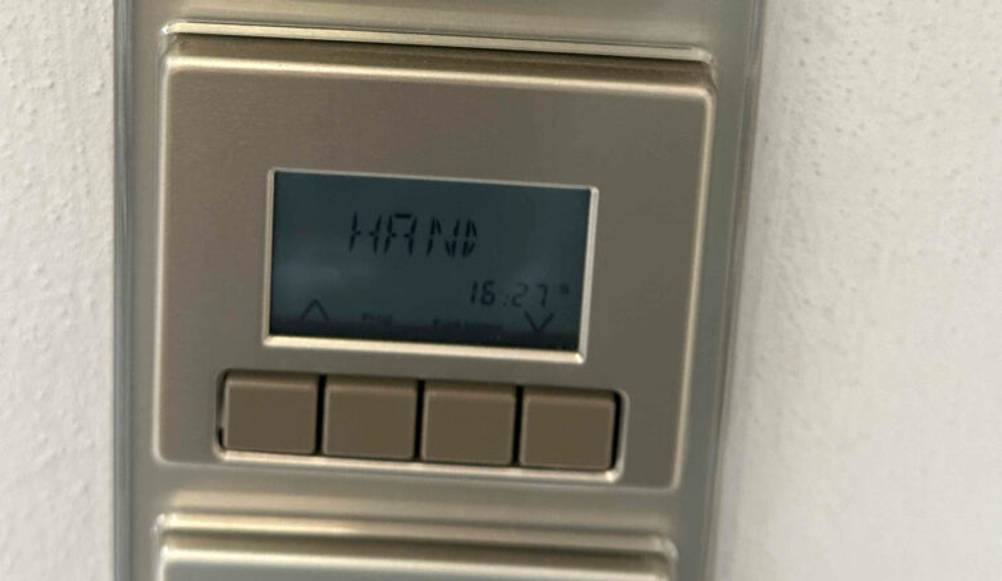 Eine eingeschaltete getestete Rollladen-Zeitschaltuhr mit LCD-Anzeige auf Hand.