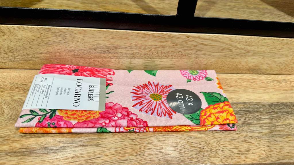 Auf einer Holzoberfläche liegt die bunte mit Blumenmuster bedruckte, getestete Stoffserviette LOCARNO von Butlers.