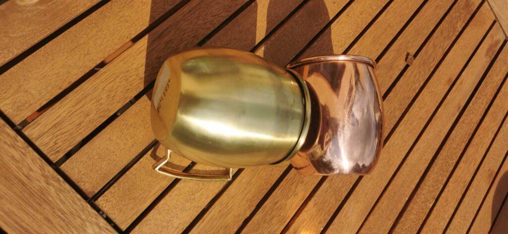 Moscow Mule Becher-Test: zwei verschiedene Becher, im Messing- sowie Kupferdesign, liegen auf einer Holzoberfläche.