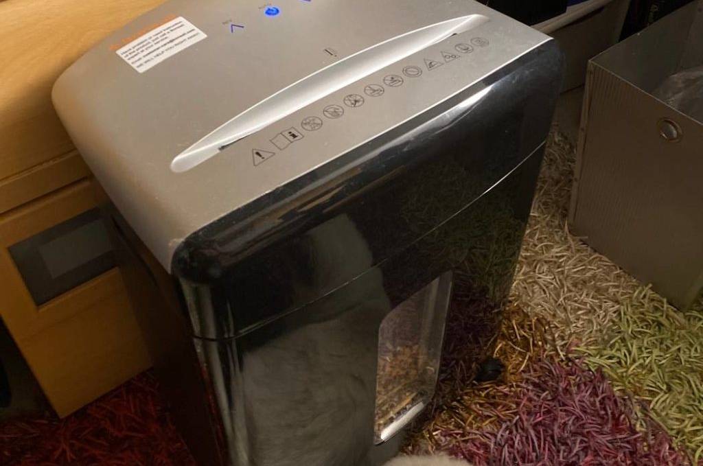 Aktenvernichter im Test: Ansicht von schräg oben eines metallfarbenen Aktenvernichters inklusive vorderem Sichtfenster in einem Bürobereich.
