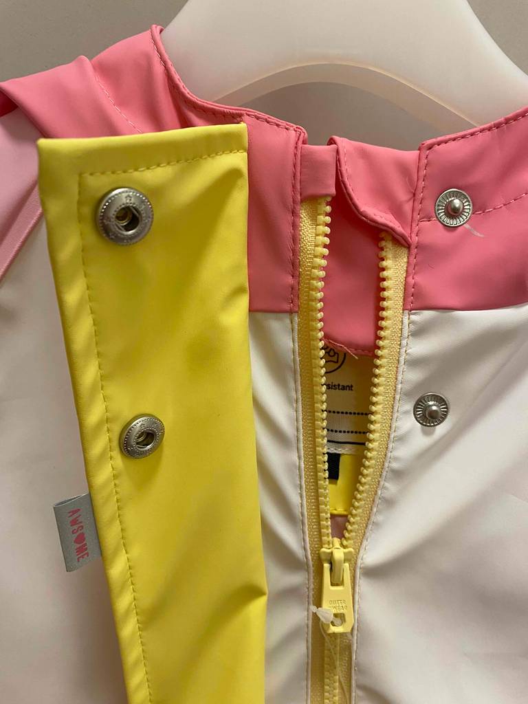 Detailansicht des oberen Reißverschlusses einer rosafarbenen, getesteten Kinder-Regenjacke.