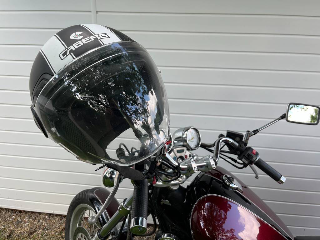 Jethelm Retro im Test: Ein schwarzer Helm mit Streifen steckt mit geschlossenem Visier auf dem Lenker eines Motorrads.