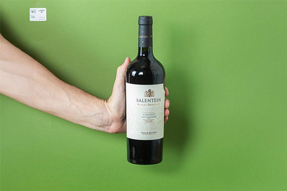 Cabernet Sauvignon im Test: Eine Flasche Cabernet-Sauvignon von Salentein von einer Hand gehalten vor grünem Hintergrund