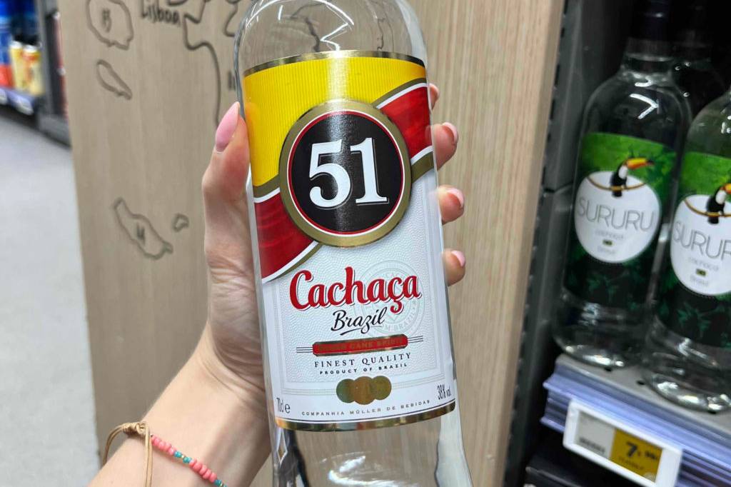 Im Test: Hand hält eine Flasche Cachaca 51 Brazil vor einem Verkaufsregal.
