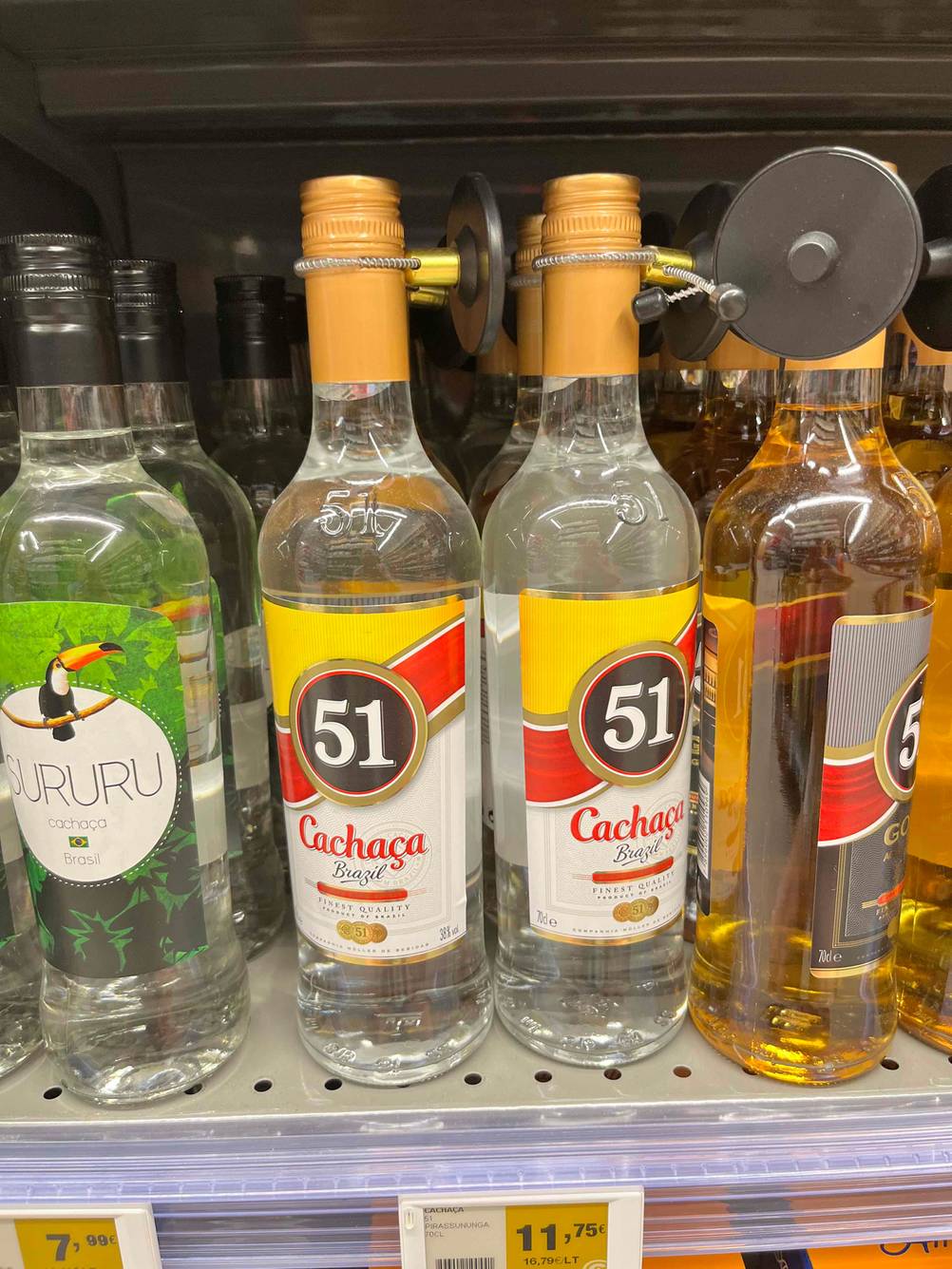 Zwei Flaschen des getesteten Cachaças neben anderen Flaschen in einem Verkaufsregal.