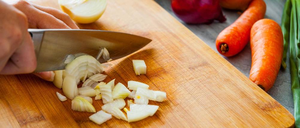 Calisso-Messer im Test: Messer schneidet Zwiebel auf einem Holzbrett