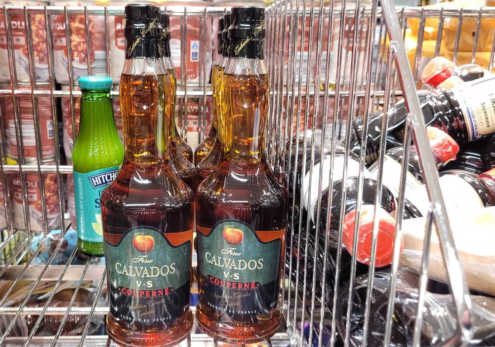 Mehrere Flaschen des Calvados im Test stehen in einem Gitterregal.