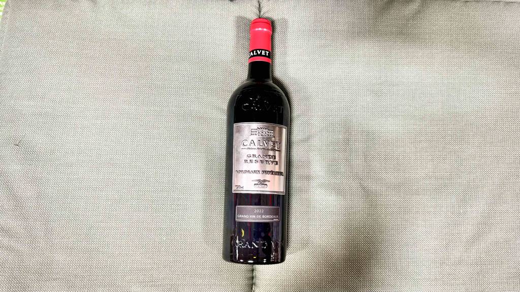 Eine Flasche getesteter Bordeaux-Wein liegt auf einer grauen Stofffläche.