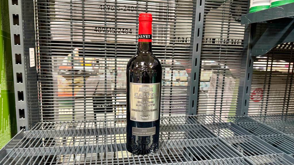 Eine Flasche Bordeaux-Wein steht zum testen in einem Gitterregal.