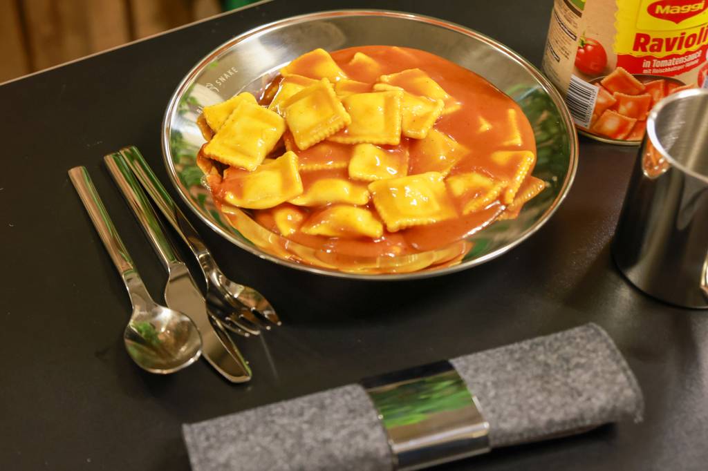 Camping-Besteck-Set-Test: Ravioli auf Teller liegen neben Camping-Besteck-Set.