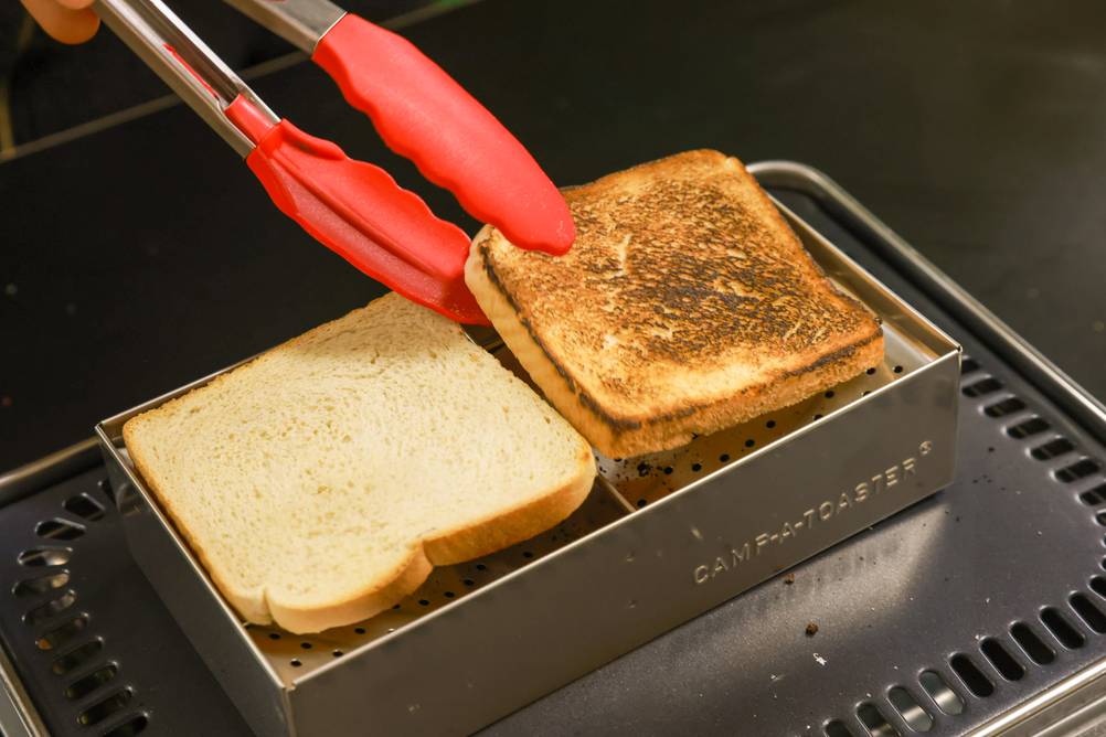 Camping-Toaster-Test: Scheibe Toast wird mit Grillzange umgedreht.