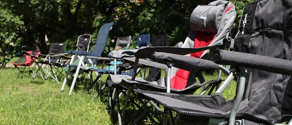 Mehrere Campingstühle stehen im Freien nebeneinander.