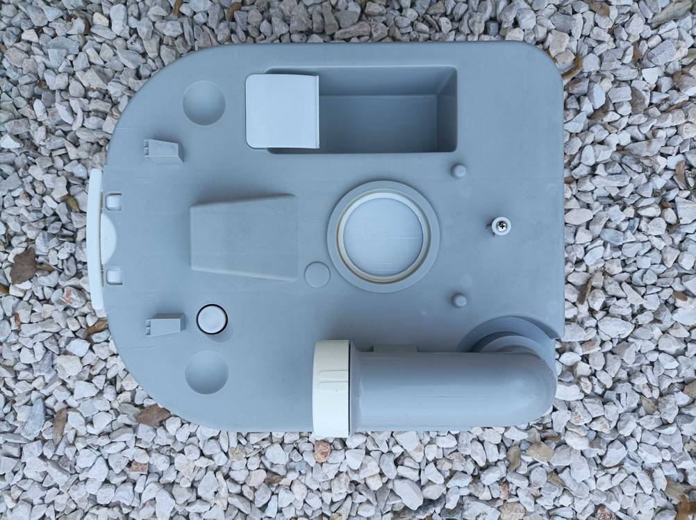 Auf einem Kieselboden befindet sich eine getestete Campingtoilette mit Spülsystem.