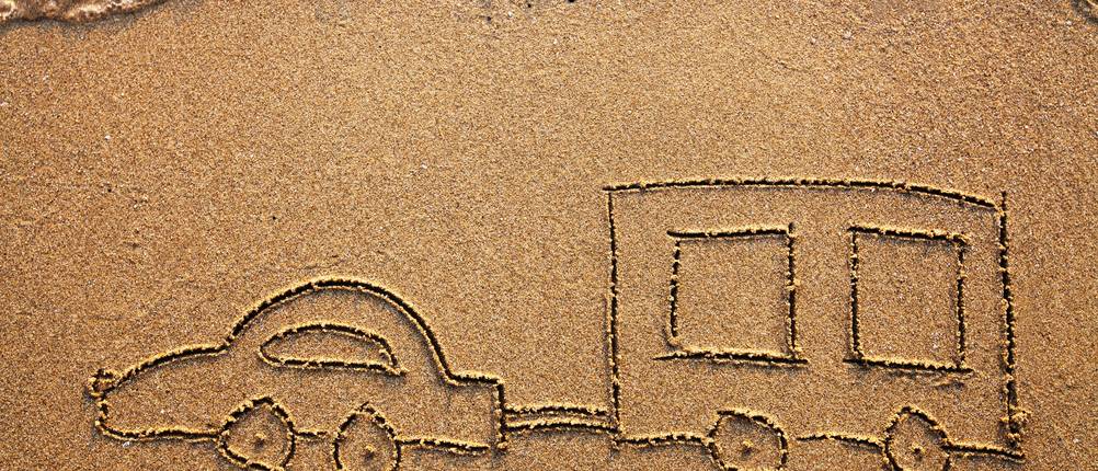 Auto und Wohnwagen im Sand gemalt.