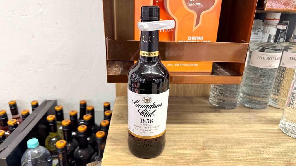 Getestet: Kanadischer Whisky in der braunen Flasche steht auf einem Holzregal neben weiteren Spirituosen.