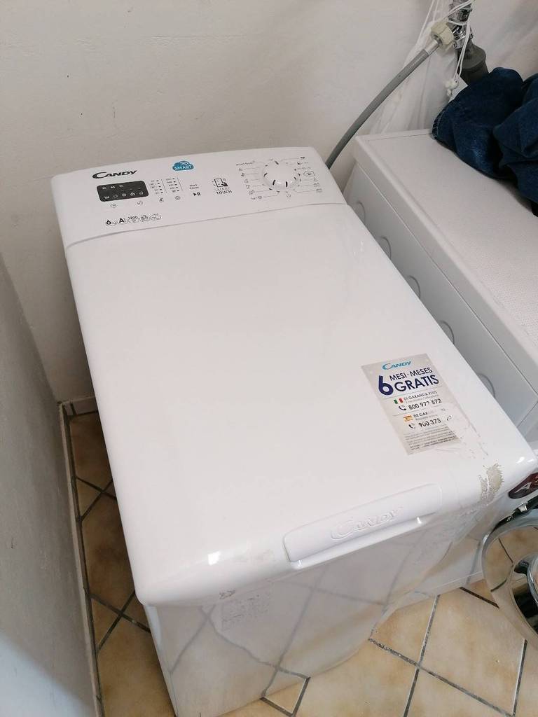 Toplader-Waschmaschine-Test: Ansicht von oben auf ein weißes, geschlossenes Modell von Candy, das in einem Waschraum steht.