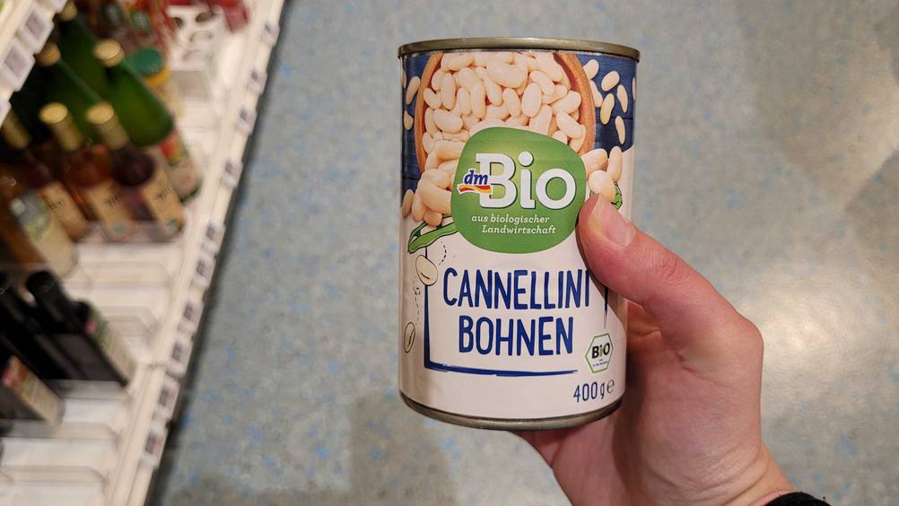 Eine Hand hält die getesteten Cannellini-Bohnen hoch.