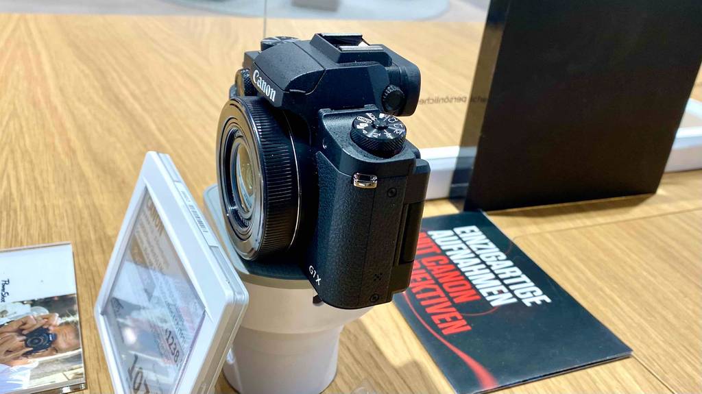 Blick von der Seite auf eine Canon Digitalkamera, die zum Testen auf einer Holzfläche steht.