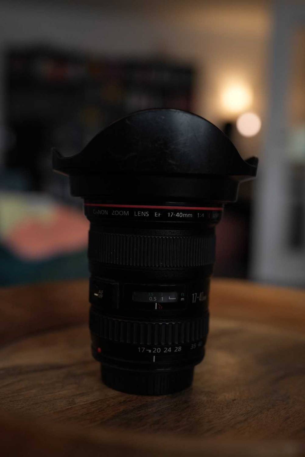 Canon Zoom Weitwinkelobjektiv im Test steht mit Gegenlichtblende auf seinem Rückdeckel auf einer Holzfläche.