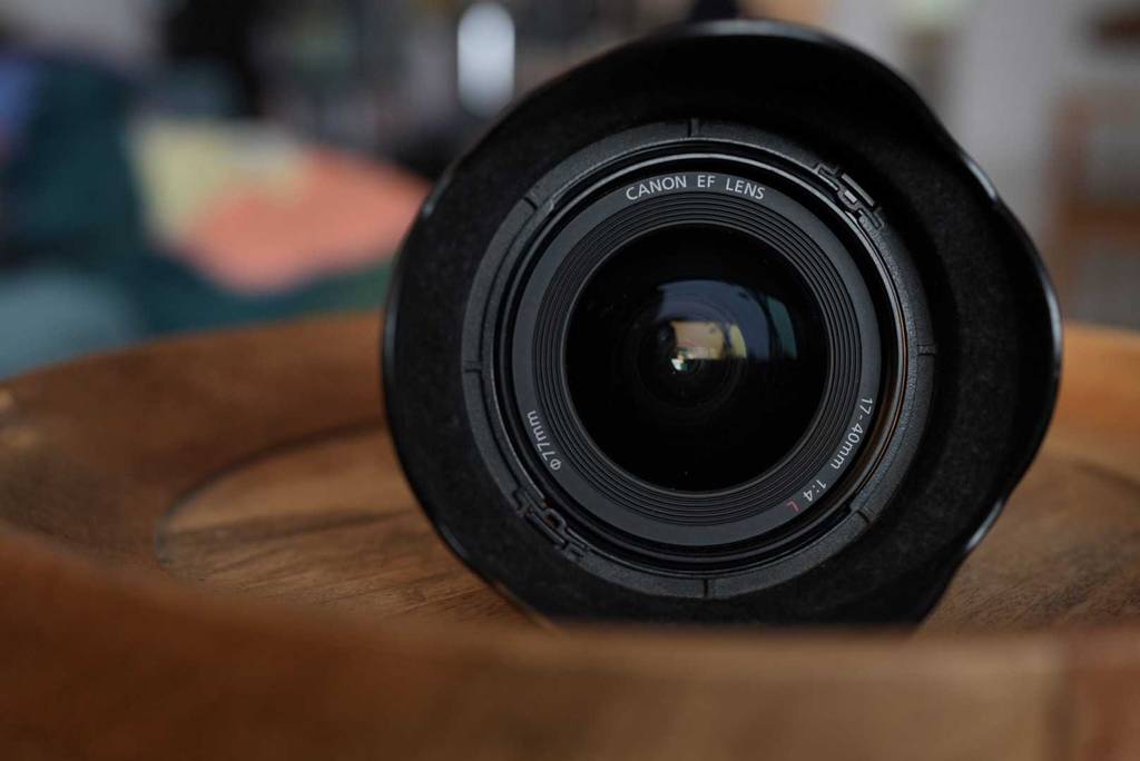 Canon Weitwinkelobjektiv im Test liegt mit Ansicht auf die 17–40 mm Linse auf einer Holzfläche.
