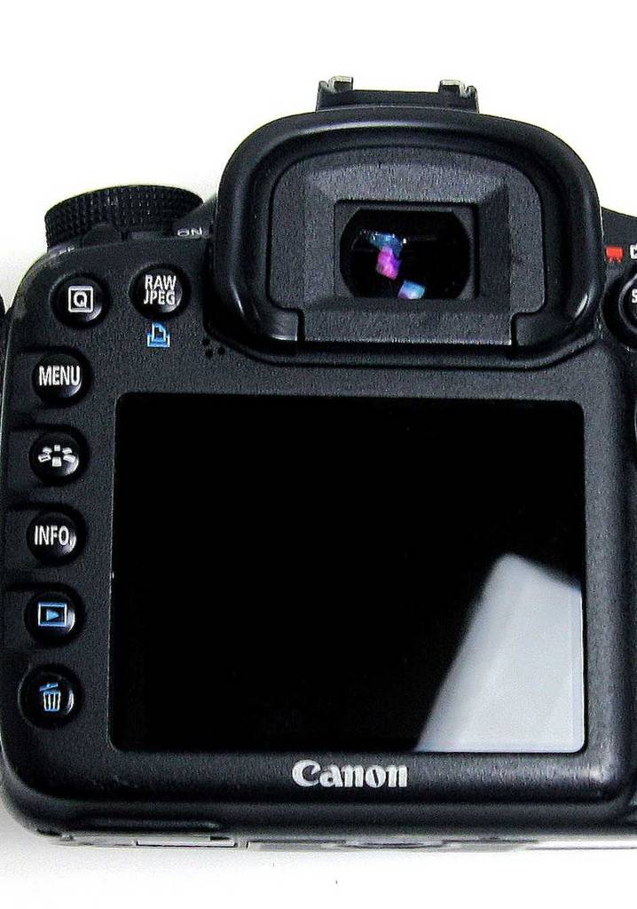 Die getestete APS-C-Kamera der Marke CANON, mit Fokus auf dem rückwärtigen Farbdisplay, steht auf einer weißen Oberfläche.