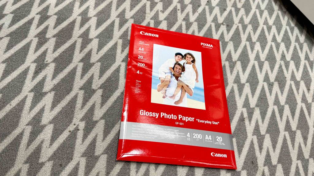 Die Verpackung von getestetem Fotopapier A4 liegt auf einem hellen Teppichboden.