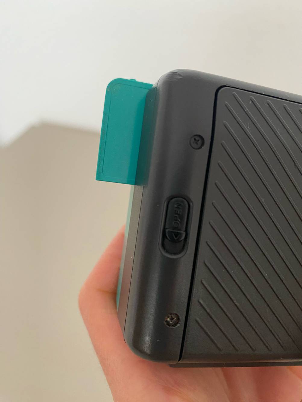 Im Test: Nahaufnahme des 'open'-Riegels einer Canon-Kompaktkamera.