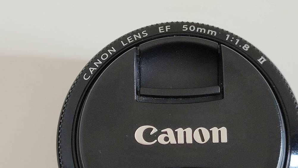 Im Test: Nahaufnahme des Aufdrucks auf der Vorderseite eines Canon-Objektivs inklusive Objektivdeckel.