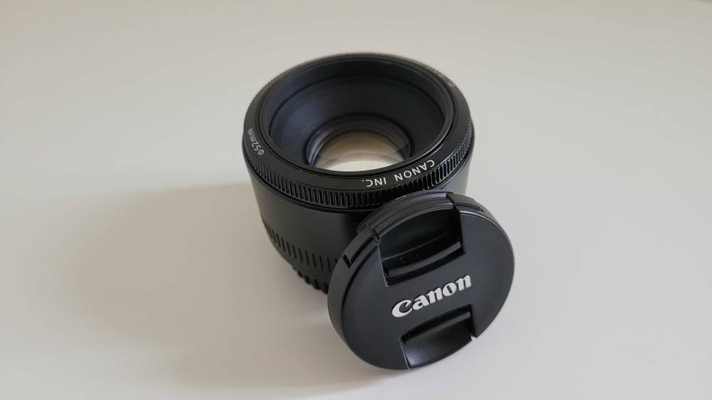 Im Test: An einem Canon-Objektiv lehnt sein Objektivdeckel auf einer hellen Fläche.