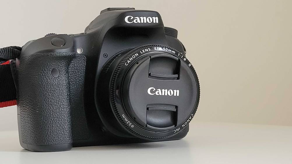 Ein getestetes Canon-Objektiv an eine Kamera von vorne auf einer hellen Fläche.