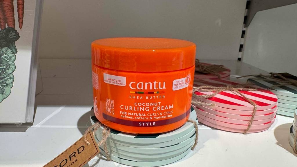 Ein Tiegel Lockencreme steht zum testen auf einem Stapel Untersetzer.