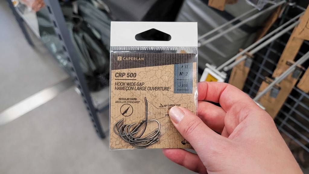 Eine Hand hält eine Packung Angelhaken zum Testen.