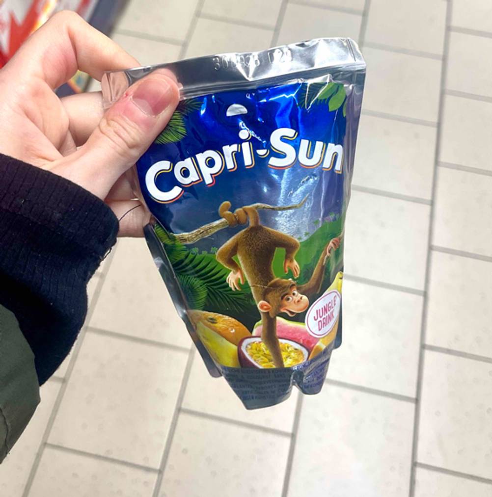 Eine Hand hält die Trinkpackung der getesteten Capri-Sun hoch.