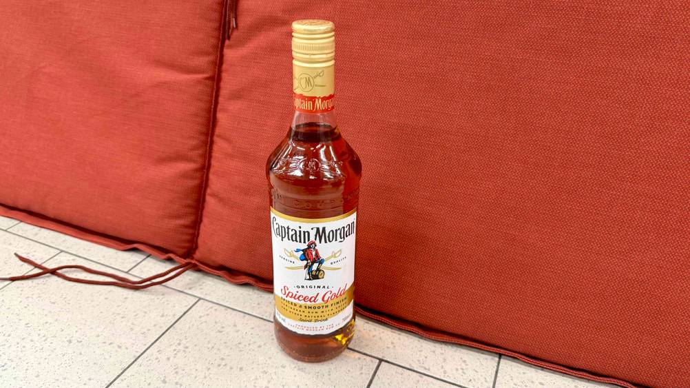 Vor einem roten Polster steht der getestete Captain Morgan auf dem Boden.