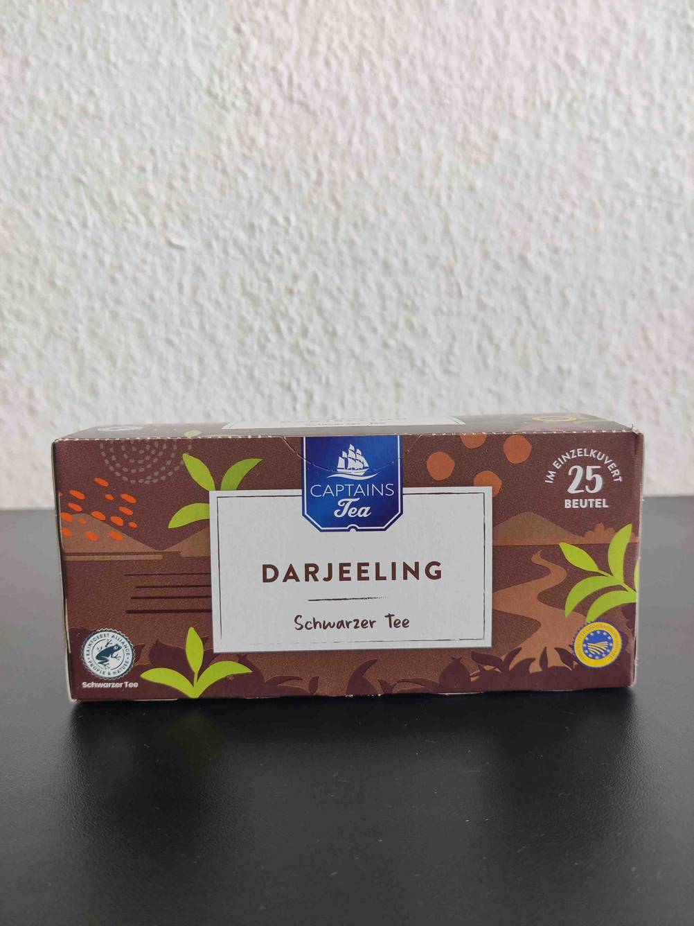Im Test: Eine Packung Darjeeling-Tee auf einer dunklen Fläche vor einer hellen Wand.