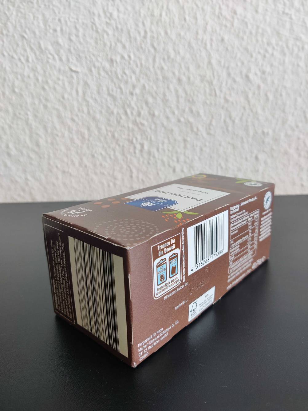 Seitenansicht einer Packung des getesteten Darjeeling-Tees auf einer dunklen Fläche.