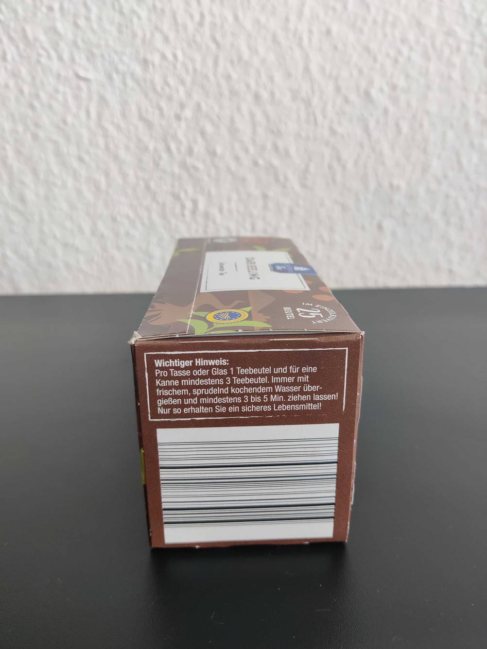Nahaufnahme einer Seite der Originalverpackung eines getesteten Darjeeling-Tees auf einer dunklen Fläche.