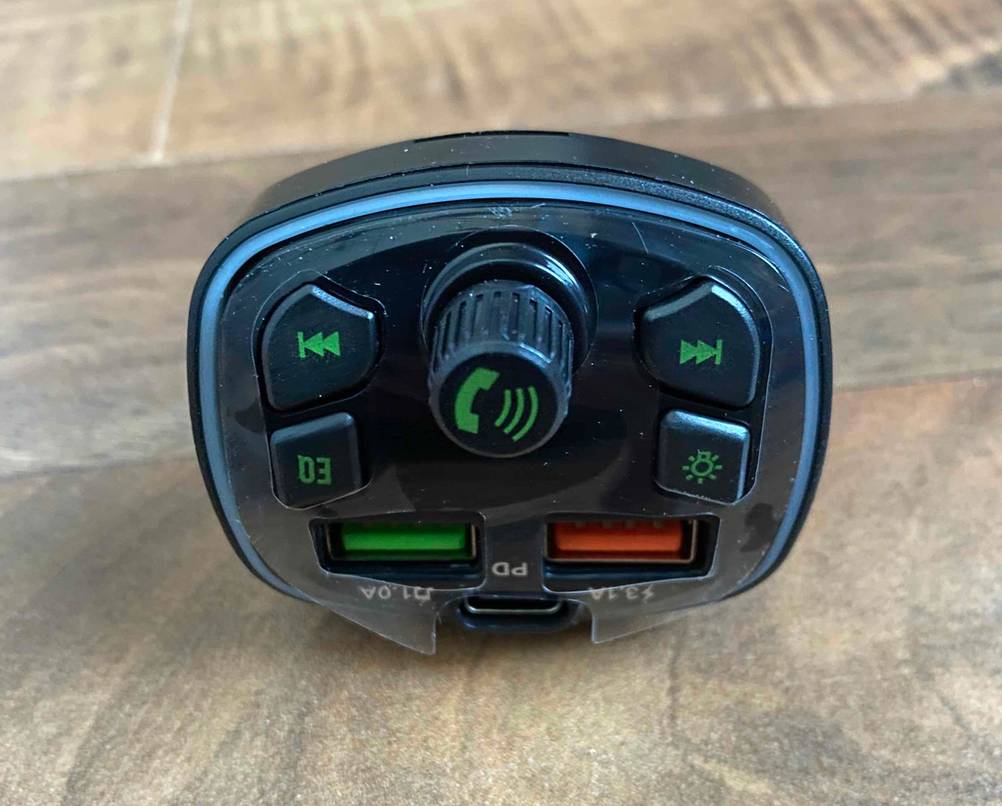 Getesteter Bluetooth-Adapter (Auto) befindet sich mit Fokus auf das integrierte Kommando-Paneel auf einem Holzuntergrund.
