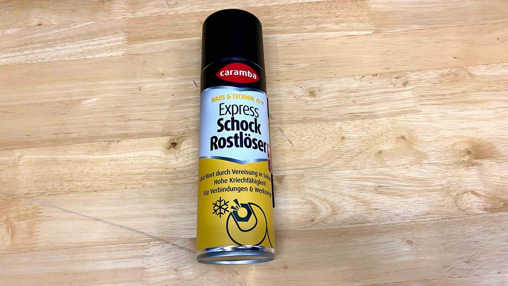Rostlöser-Test: Caramba Express Schock Rostlöser in einer Sprühdose im schwarz-weiß-gelben Design liegt auf einer Holzfläche.