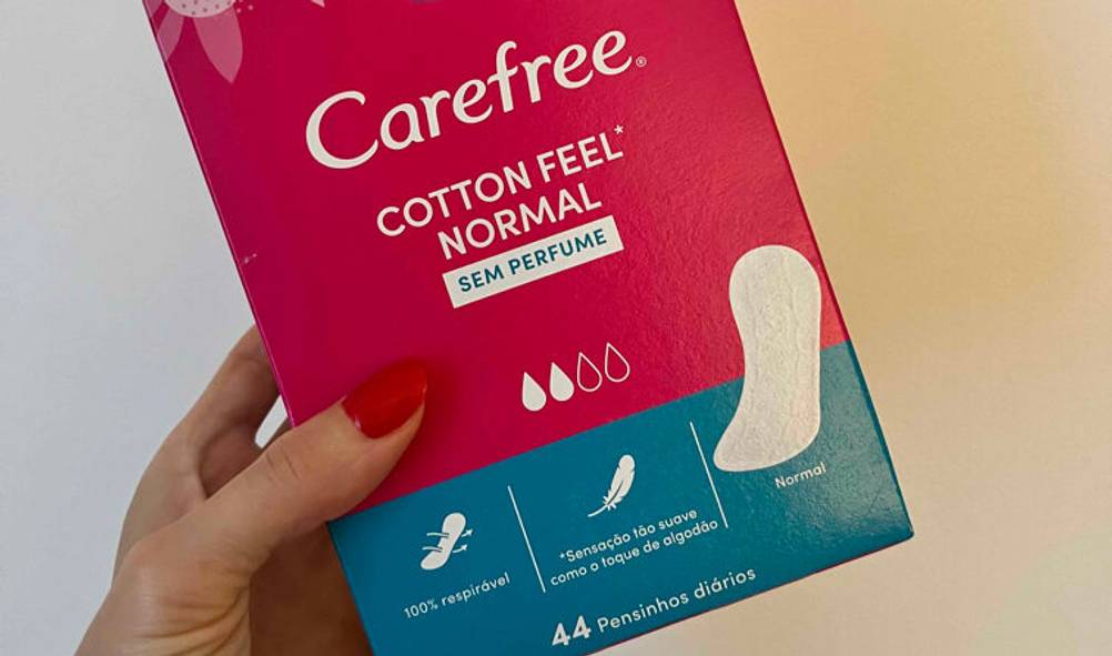 Eine Damenhand hält eine Packung mit getesteten Slipeinlagen der Marke Carefree vor einem hellen Hintergrund.