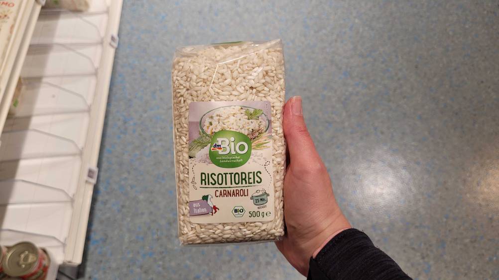 Eine Hand hält den getesteten Carnaroli-Reis hoch.