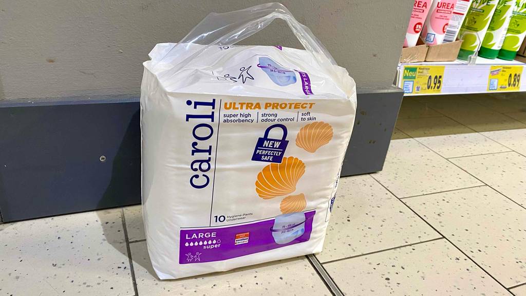 Windeln für Erwachsene im Test: eine weiße Packung Caroli Windeln steht auf einem hellen Fliesenboden im Verkaufsbereich.