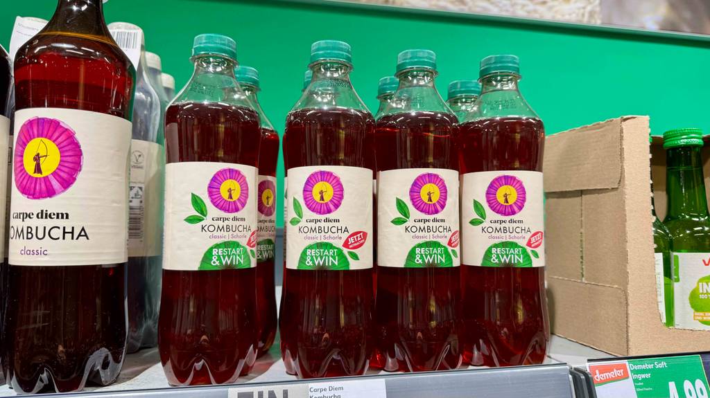 Kombucha im Test: Mehrere transparente Flaschen mit roter Flüssigkeit stehen nebeneinander in einem Verkaufsregal.