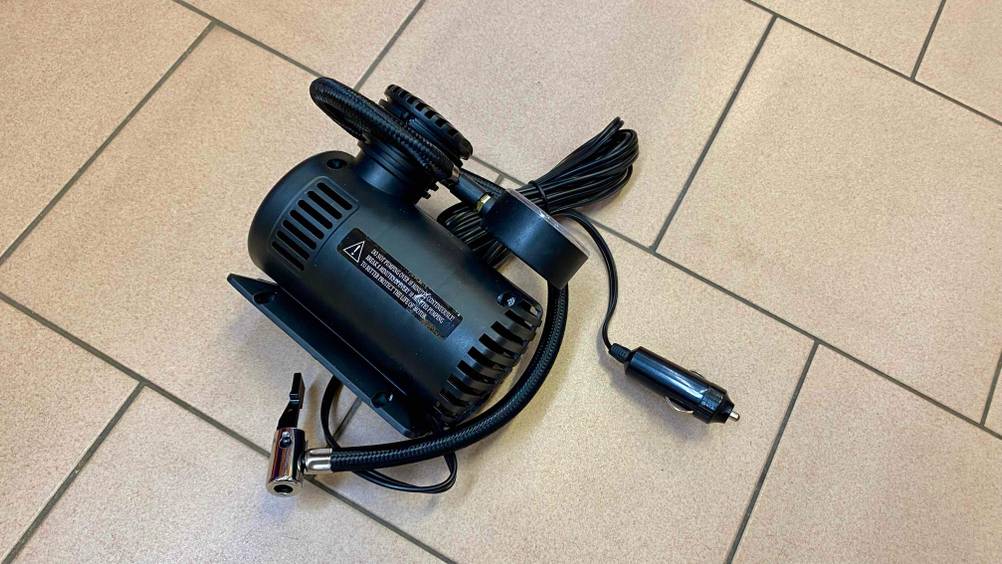 Im Test: Ein 12V-Kompressor auf der Seite liegend auf einem Fließenboden.